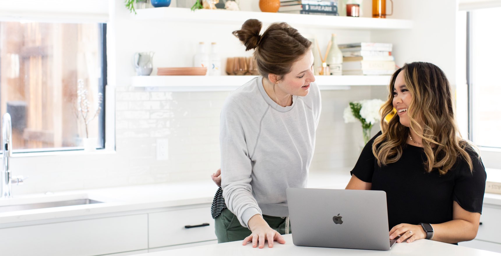 Professional women smile and discuss information on laptop