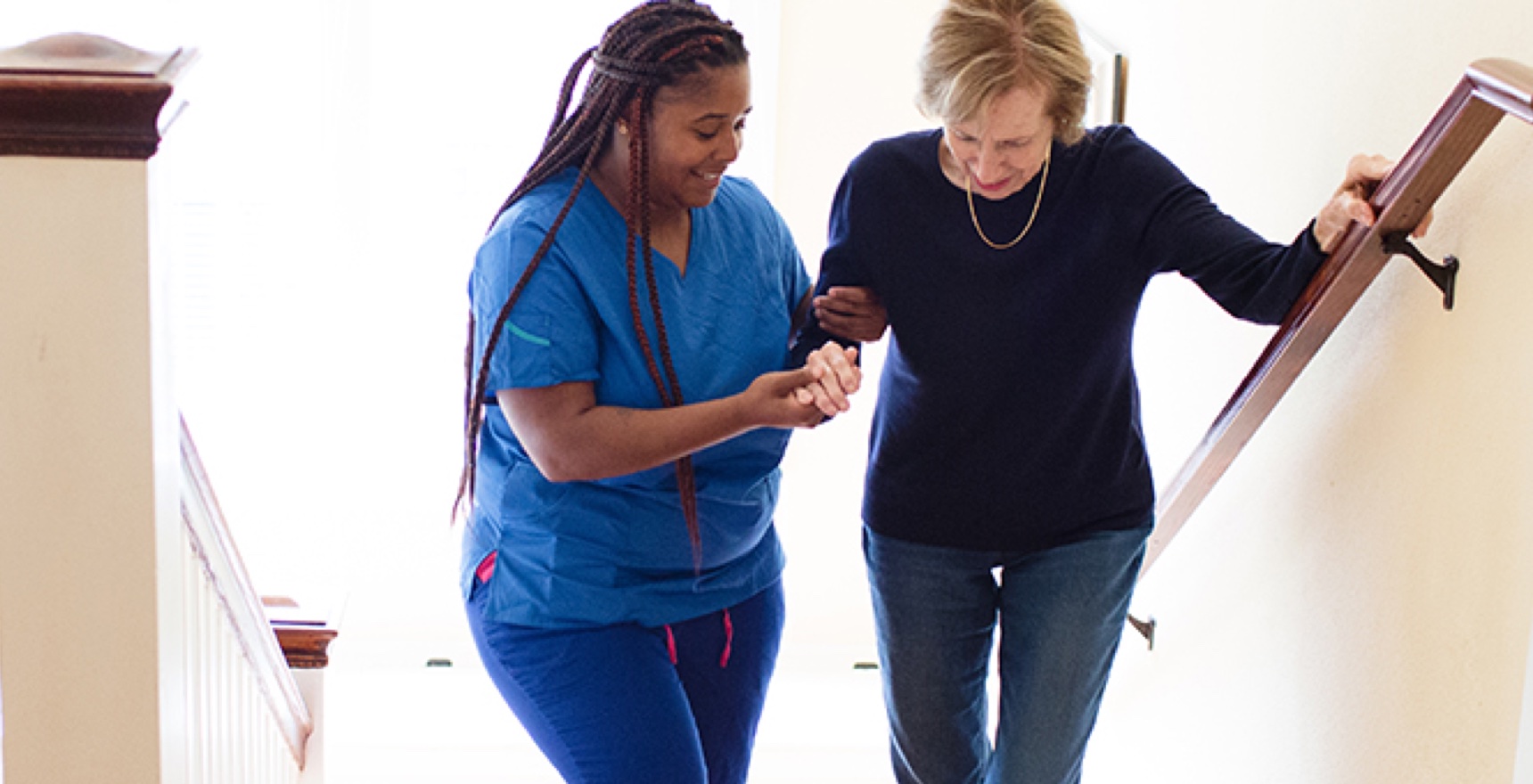 Care Professional helps aging woman up the stairs