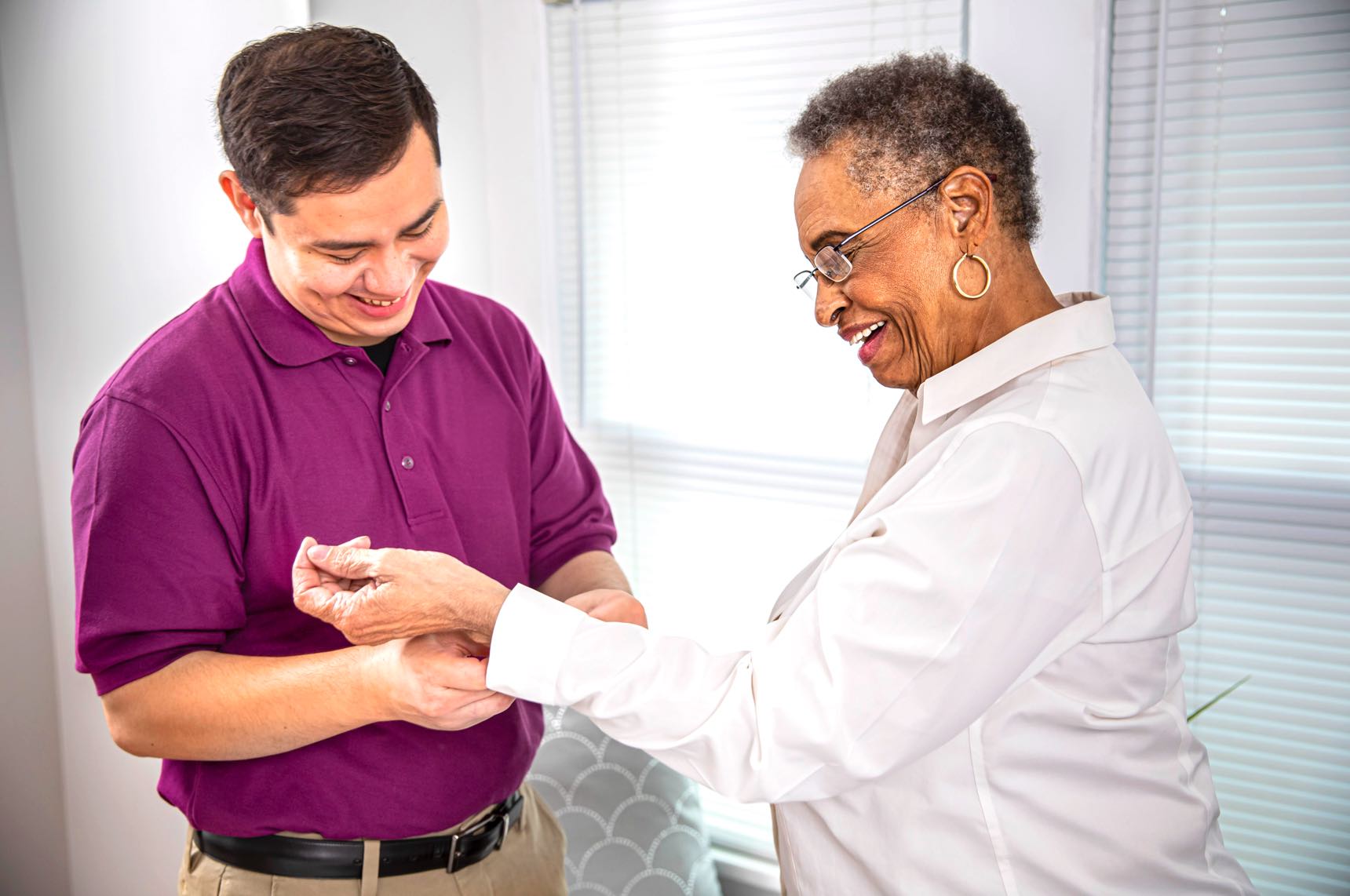 care-professional-happily-assists-aging-woman-with-sleeve-buttons.jpg