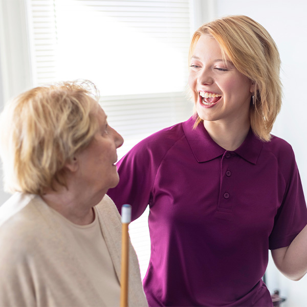 Aging woman and care professional happily play pool together