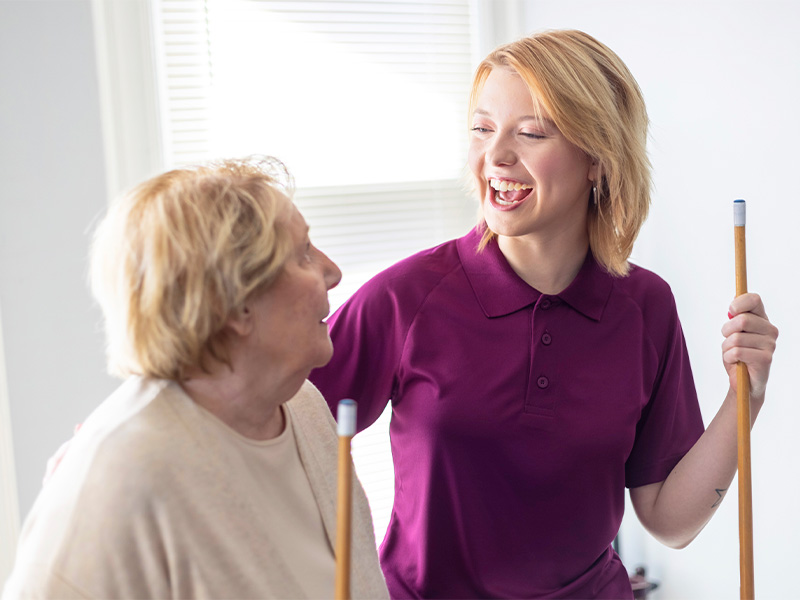 Aging woman and care professional happily play pool together