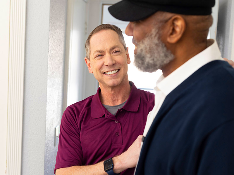 Care Professional assists aging man in vestibule