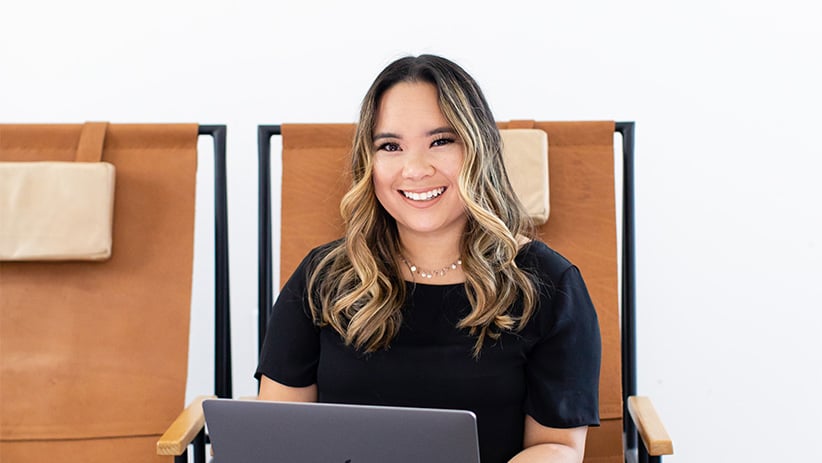 Young professional woman smiling while sitting and working from laptop