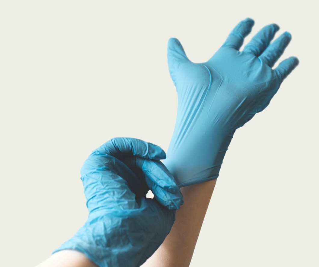 Two hands putting on latex gloves