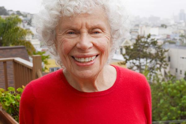 Aging woman stands on back patio overlooking city