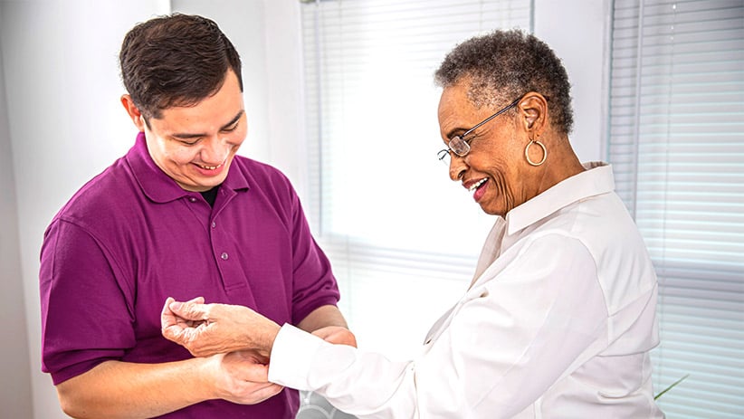 Aging woman smiling while receiving help from a care professional